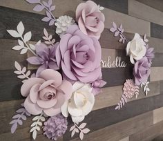 paper flowers are arranged on the wall in front of a wooden sign that reads,'personalized '