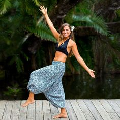 a woman standing on a dock with her arms in the air while wearing a black top