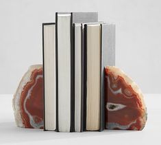 two books are stacked on top of each other in front of an orange and white rock