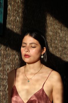 a woman with her eyes closed standing in front of a wall wearing a brown dress