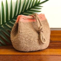 a crocheted bag sitting on top of a wooden table next to a plant