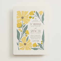 a wedding card with yellow flowers and green leaves on the front, printed in white paper