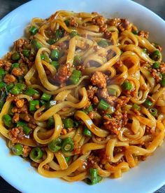 a white bowl filled with noodles and meat