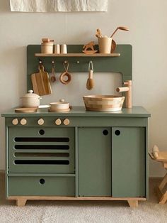 an old fashioned kitchen with green cabinets and wooden utensils on the stove top