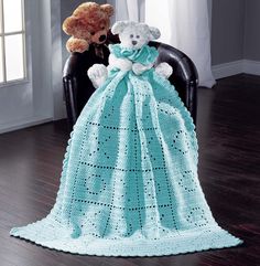 two teddy bears sitting on a chair with a crocheted blanket