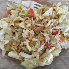 a close up of a salad on a plastic plate with a fork in the background