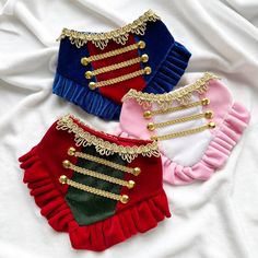 three pieces of clothing with gold chains and red, pink, blue, and green trims