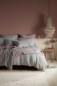 a bedroom with pink walls and grey bedding