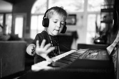 a young boy wearing headphones and listening to music on an electronic keyboard in his living room