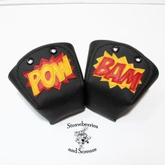 two black and red leather wrist pads with the word pow on each side, set against a white background