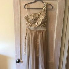 a dress hanging on a door with a hanger in front of it that has gold sequins