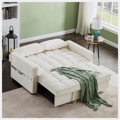 a white futon bed sitting on top of a wooden floor next to a window