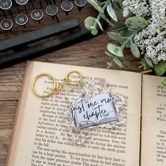 an open book sitting on top of a wooden table next to a keychain