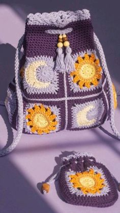 a crocheted purse and matching handbag are sitting on a purple surface in the sunlight