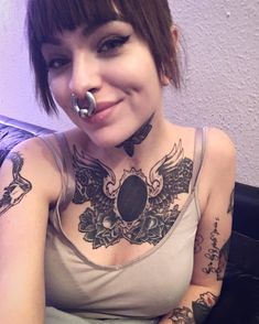 a woman with tattoos on her chest and nose