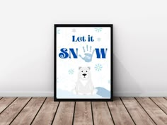 a framed poster with the words let it snow and a polar bear sitting in front of it