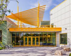 the front entrance to an office building with bicycles parked outside and yellow awnings