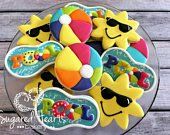 decorated cookies in the shape of sunflowers and beach balls on a glass plate