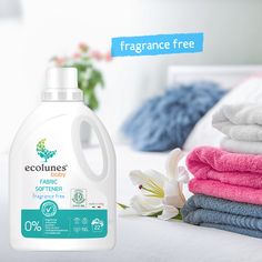 a bottle of ecoline's fabric softener next to folded towels on a bed