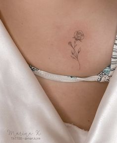 a woman's stomach with a single flower tattoo on her left side ribcage