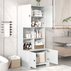 a bathroom with white cabinets and towels on the shelf next to the bathtub is shown