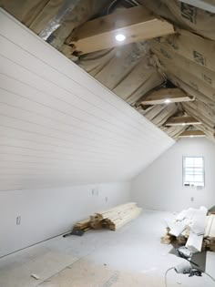 an unfinished attic with exposed wood beams and white walls that have been stripped off from the ceiling