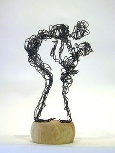 a sculpture made out of wire on top of a wooden base with a white background