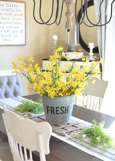 a dining room table with flowers in a bucket