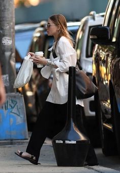 a woman is walking down the street with her coffee