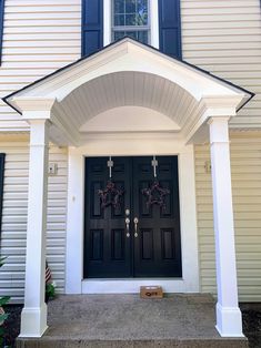 a black front door with two wreaths on it