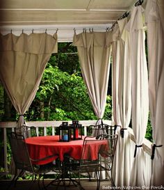 an outdoor dining area with curtains and table