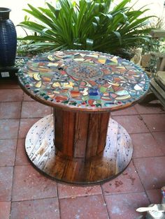 a round table made out of wood and glass mosaics on it's sides