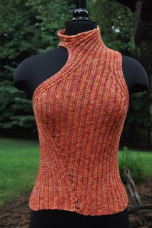 an orange knitted top on a mannequin with trees in the back ground