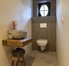 a bathroom with a sink, toilet and stool in it's corner next to a window