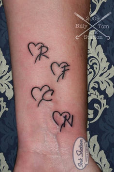 a small wrist tattoo with hearts on it