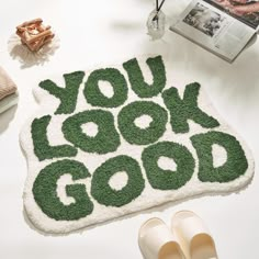 a rug with the words you look good on it next to shoes and other items