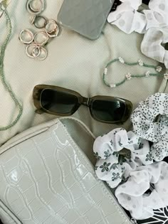 an assortment of accessories including sunglasses, bracelets and purse on a table with flowers