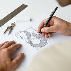 a person is drawing on paper with scissors