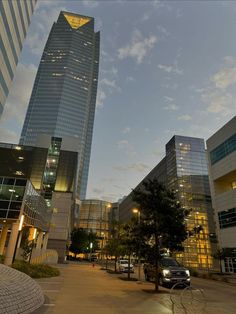 two tall buildings are lit up at night in the background is a parking lot with parked cars