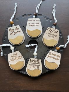 six wine bottle tags hanging from a metal plate on a wooden table with white string