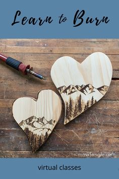 two wooden heart shaped ornaments sitting on top of a wooden table next to a pen