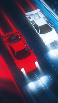 two red and white cars driving down a street at night with bright lights on them