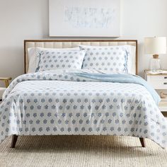 a bed with blue and white bedspread in a bedroom next to a painting