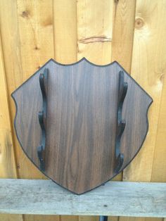 a wood and metal wall mounted clock on a wooden fence with an iron frame in the shape of a shield