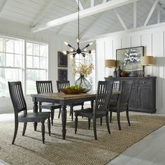 a dining room table with chairs and a bowl of fruit on top of the table