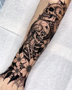 a person with a skeleton and flowers tattoo on their arm