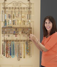 a woman standing next to a wall mounted jewelry rack