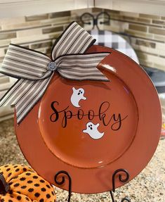 an orange plate with two ghost faces on it and the words spooky painted on it