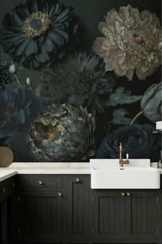 a black and white floral wallpaper in a bathroom with dark wood cabinets, gold faucets and a sink