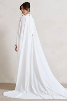 Exuding an angelic, ethereal mood, this aptly-named maxi dress was designed to see you through your big day. Crafted in a luxurious cream shade of our signature crepe, Saint arrives in a fully satin lined silhouette equipped with shaping seams that flow down your front and back. What transcends this piece is a couture-like chiffon cape that effortlessly flows behind you as you make your way down the aisle. Pair yours with our Just A Fling court shoes for a match made in heaven.   Features  - Premium crepe fabric - Premium chiffon cape - High neckline  - Self-tie collar - Princess seams - Invisible zip closure  - High leg split - Maxi length    Sizing & Fit  Model is 5'8 and wears UK size 8 / US size 4   Product Information     Fully lined with no stretch  Premium crepe in Cream (100% P Elegant Cape Sleeve Maxi Dress For Wedding, Elegant Maxi Dress With Cape Sleeves For Wedding, White Maxi Length Gown For Banquet, Wedding Maxi Dress With Sweep Train, Flowy Floor-length Evening Dress For Weddings, Fitted Cape Maxi Dress For Wedding, Wedding Cape Maxi Dress Fitted, White Chiffon Evening Maxi Dress, Flowy Chiffon Wedding Gown